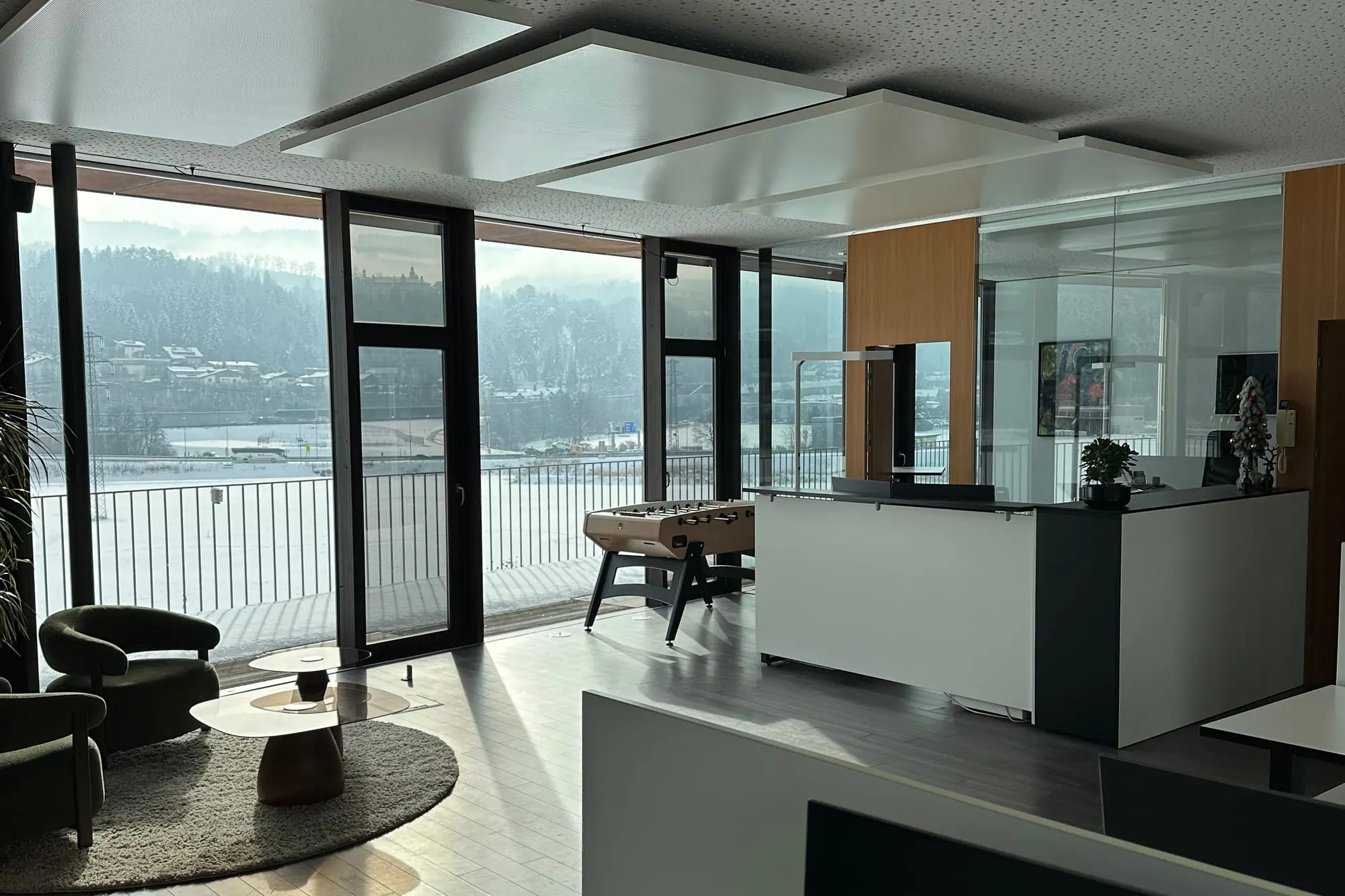 Die Lounge mit grünen Sesseln und Tischfußball vor der Fensterfront
