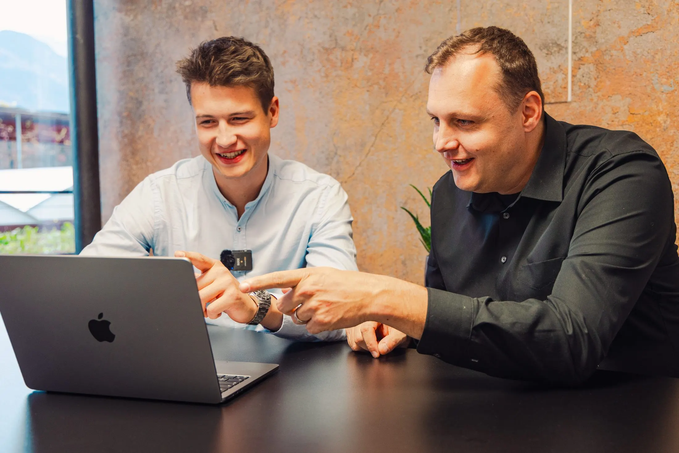 Zwei Kaino-Mitarbeiter besprechen sich an einem Tisch mit Laptop